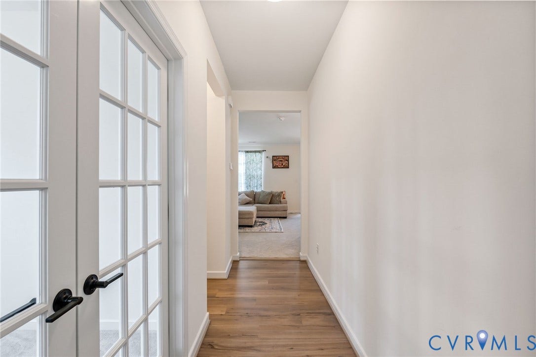 French doors with matte black hardware, wood-finish flooring, and white painted walls