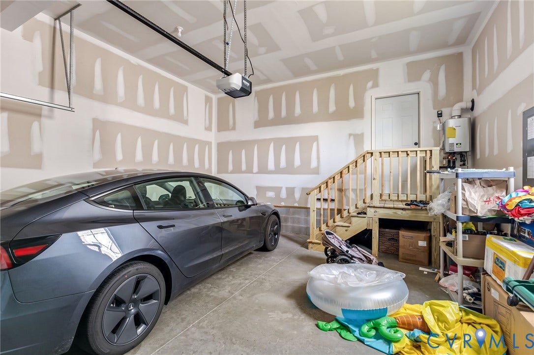 Garage space with concrete flooring, automatic garage door opener, and unfinished drywall