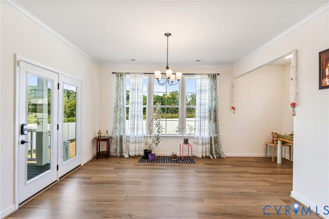 Wood-finish flooring, white trim, crown molding, double glass-paneled doors, and a multi-pane window