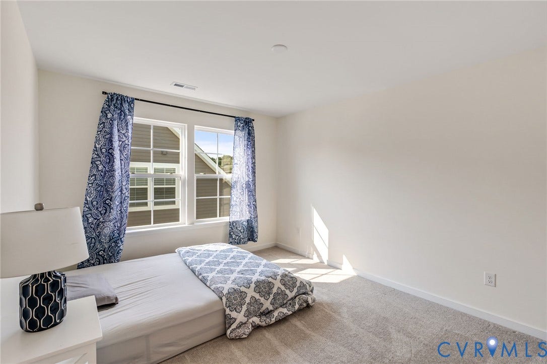 Room featuring neutral wall tones, two large windows, and soft carpet flooring