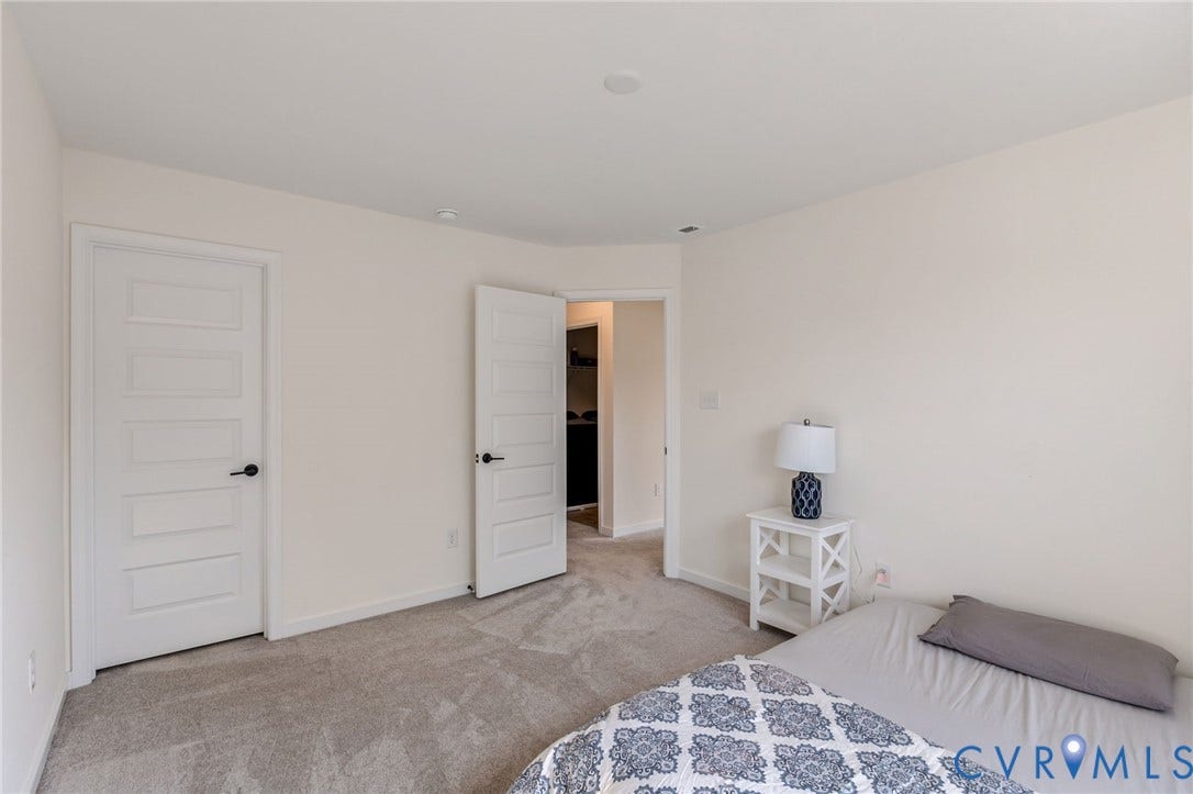 Plush carpet flooring, recessed lighting, and white paneled doors with matte black hardware
