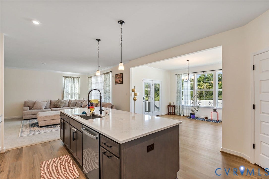 Kitchen island with a built-in sink, stainless steel dishwasher, and pendant lighting