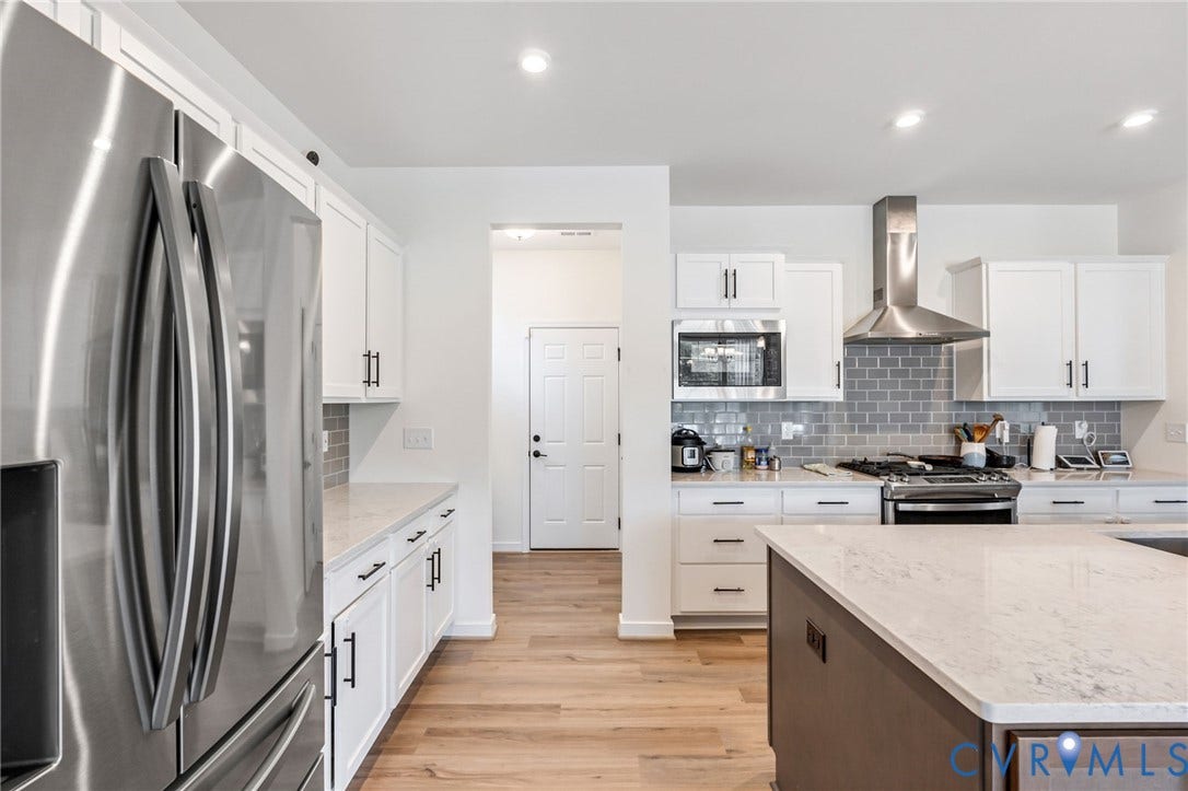 Kitchen featuring white cabinetry, stainless steel appliances, light-toned countertops, a subway tile backsplash, and wood-finish flooring