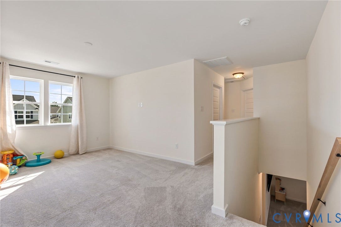 Carpeted landing area featuring a double window, white trim, and a staircase with a wood handrail