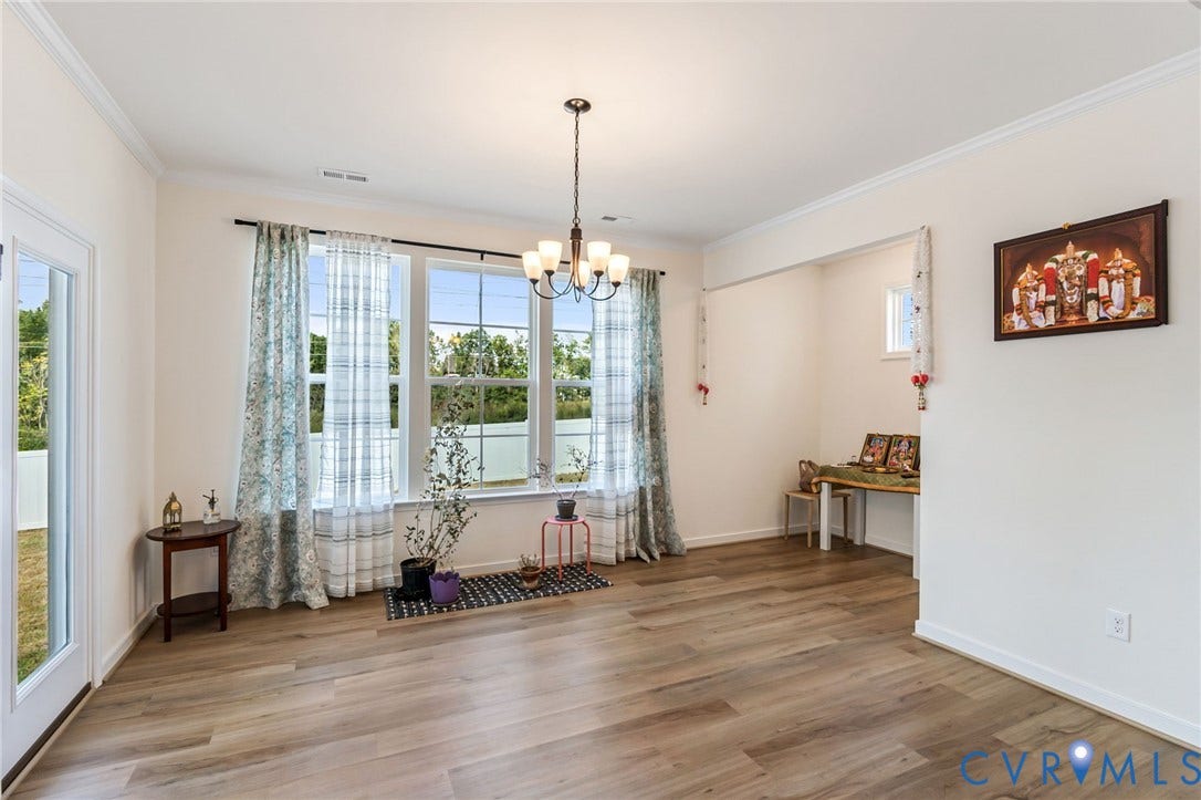 Wood-finish flooring, multiple large windows, crown molding, a built-in recessed area, and an overhead chandelier