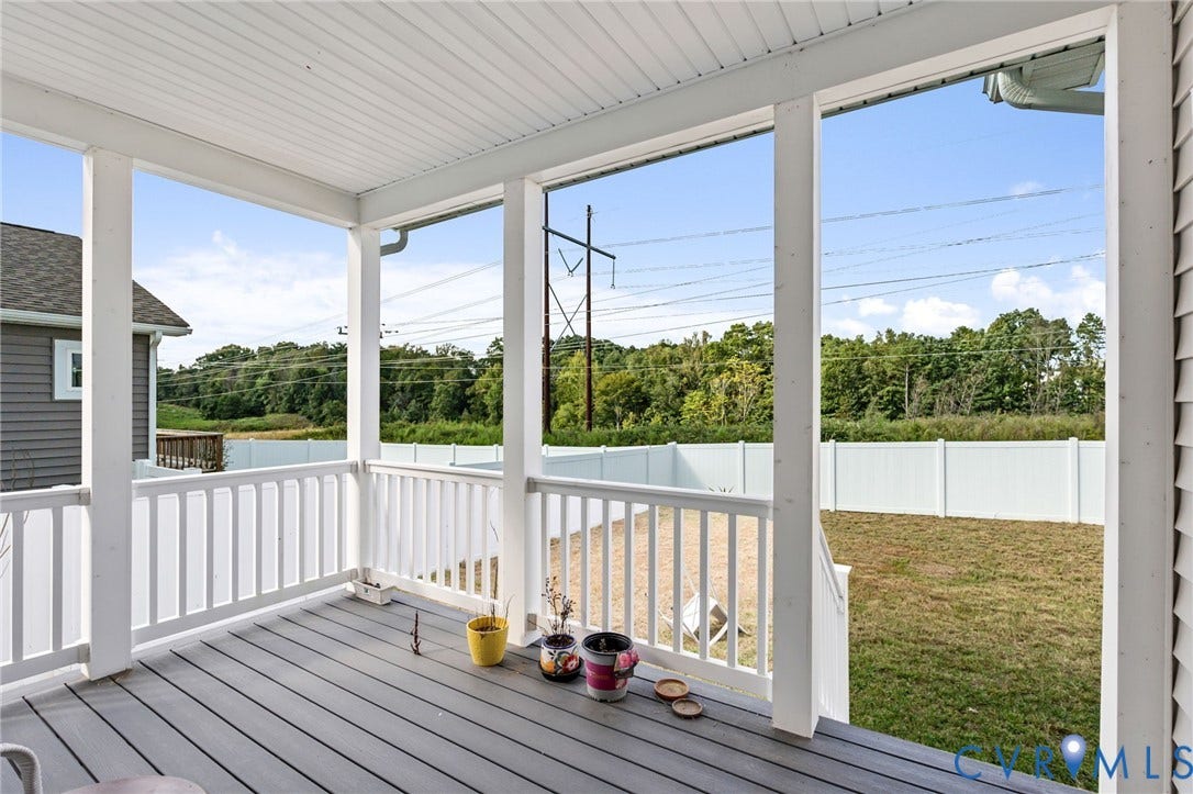 Covered porch with composite decking, white railing, white vinyl soffit, and white gutters