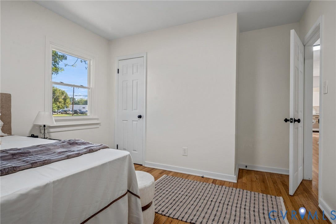 Hardwood flooring, white painted walls, white trim, and interior panel doors with dark hardware