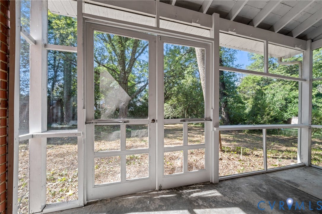 Screened porch featuring a concrete floor, white-painted wood framing, and clear double glass doors