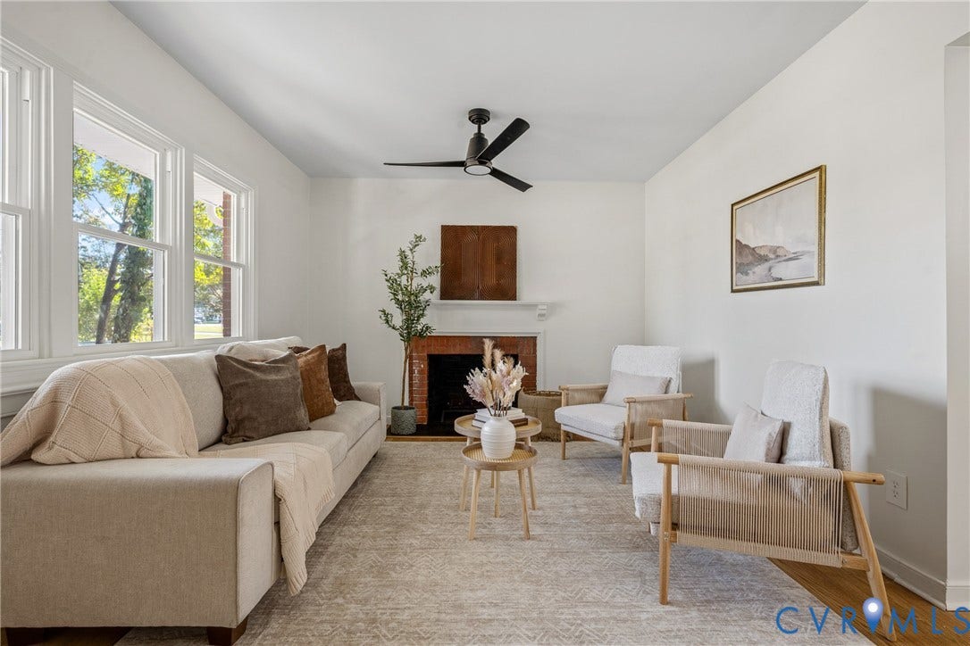 White walls with wood-finish flooring, a brick fireplace with a white mantel, and ceiling fan