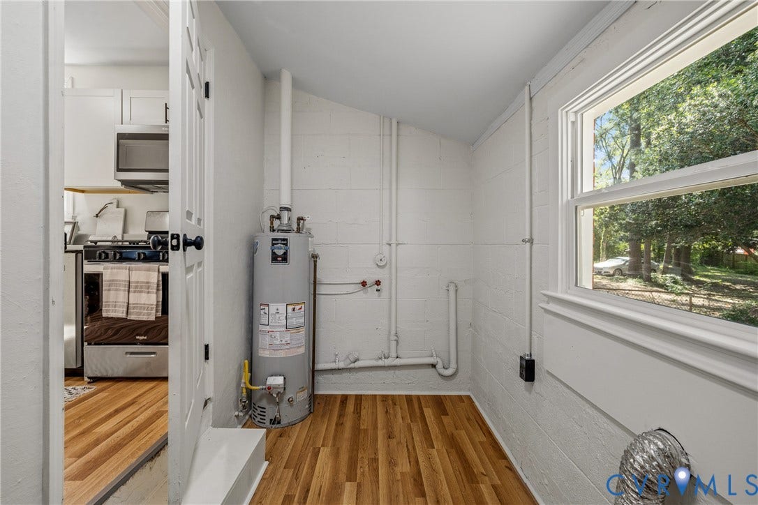 Interior room with wood-finish flooring, white painted block walls, and a window providing natural light