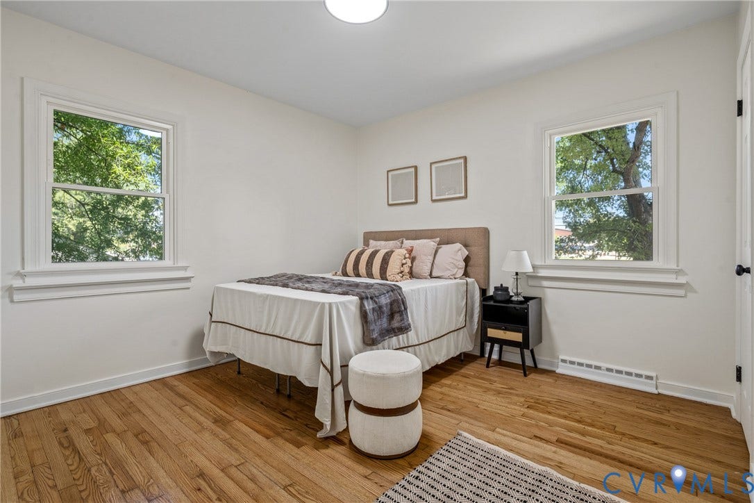 Hardwood flooring, painted white walls, two windows with white trim, and a ceiling-mounted light fixture