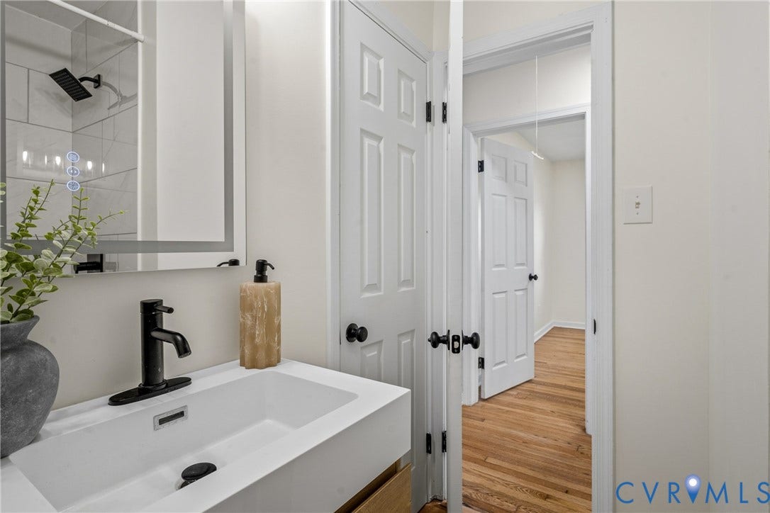 Floating vanity with an integrated rectangular sink, matte black faucet, and an illuminated mirror