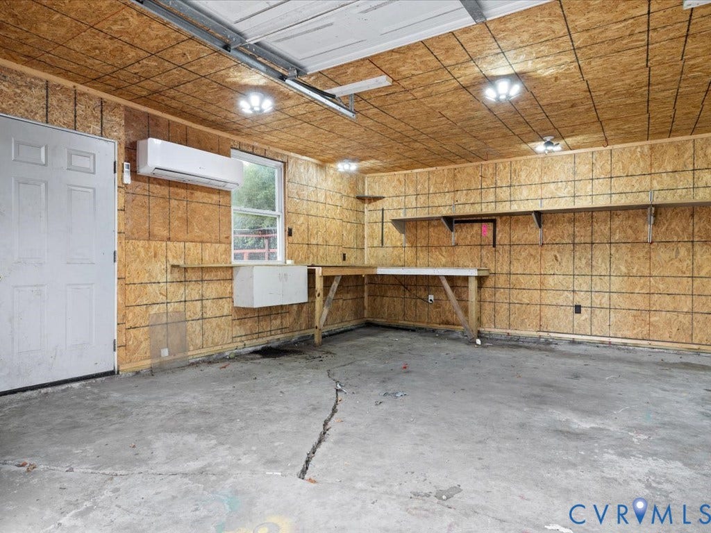 Garage workspace featuring built-in shelving, concrete flooring, and an installed mini-split unit