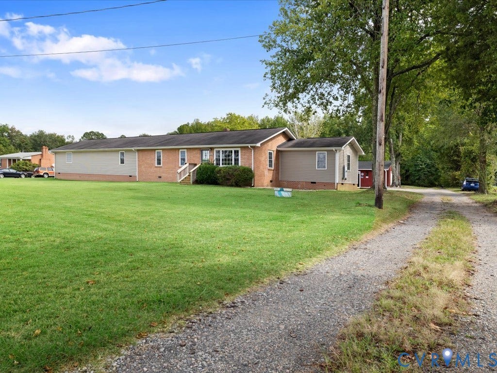 Brick and siding exterior with a gravel driveway