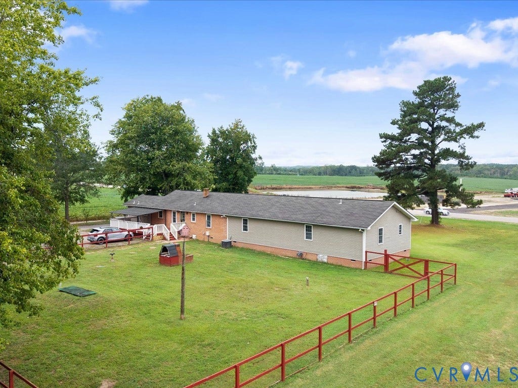 Expansive green lawn with red fencing, mature trees