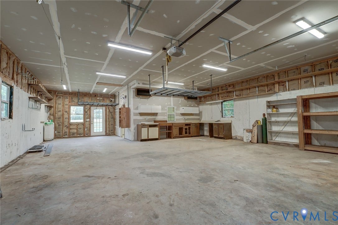 3120 McQuinn Road, Powhatan, VA 23139 Spacious garage featuring a concrete floor, built-in cabinetry, overhead lighting, and an overhead storage rack