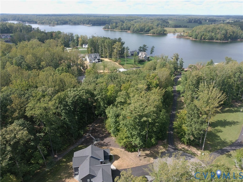 0 Wolftrap Court, Lighthouse, Bumpass, VA 23024 Expansive natural surroundings featuring a large body of water, mature trees, and a residential property with a dark-toned exterior