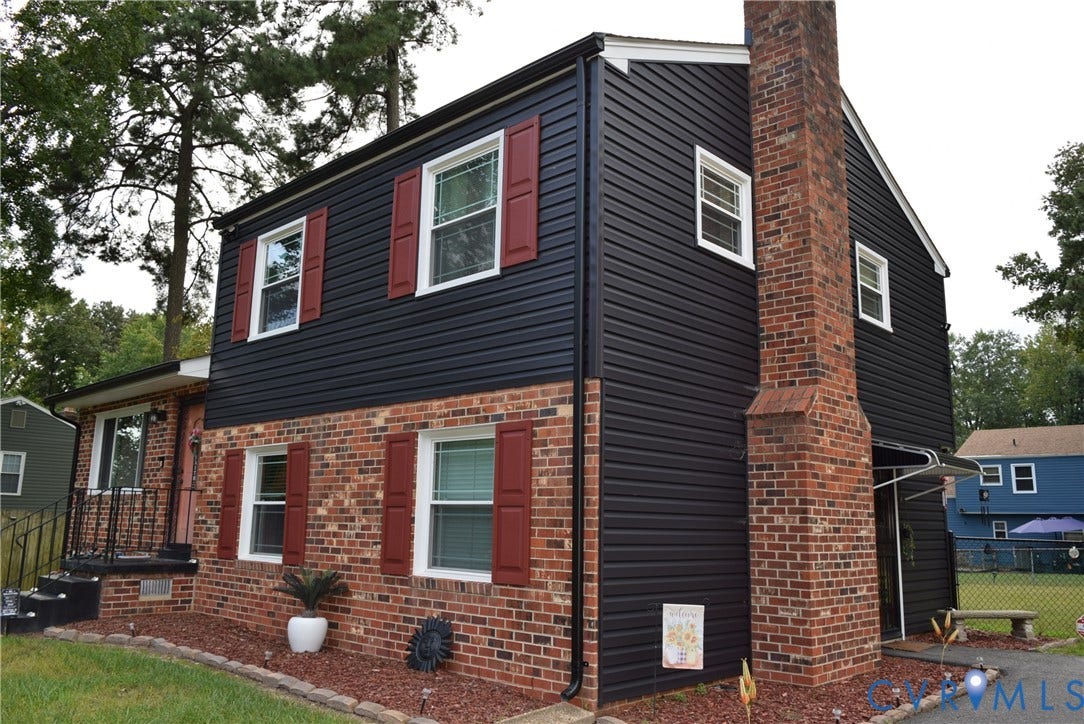 3102 Oxnard Road, Henrico, VA 23223 Brick and siding exterior featuring red shutters, a prominent brick chimney, and a landscaped front yard with a defined planting bed