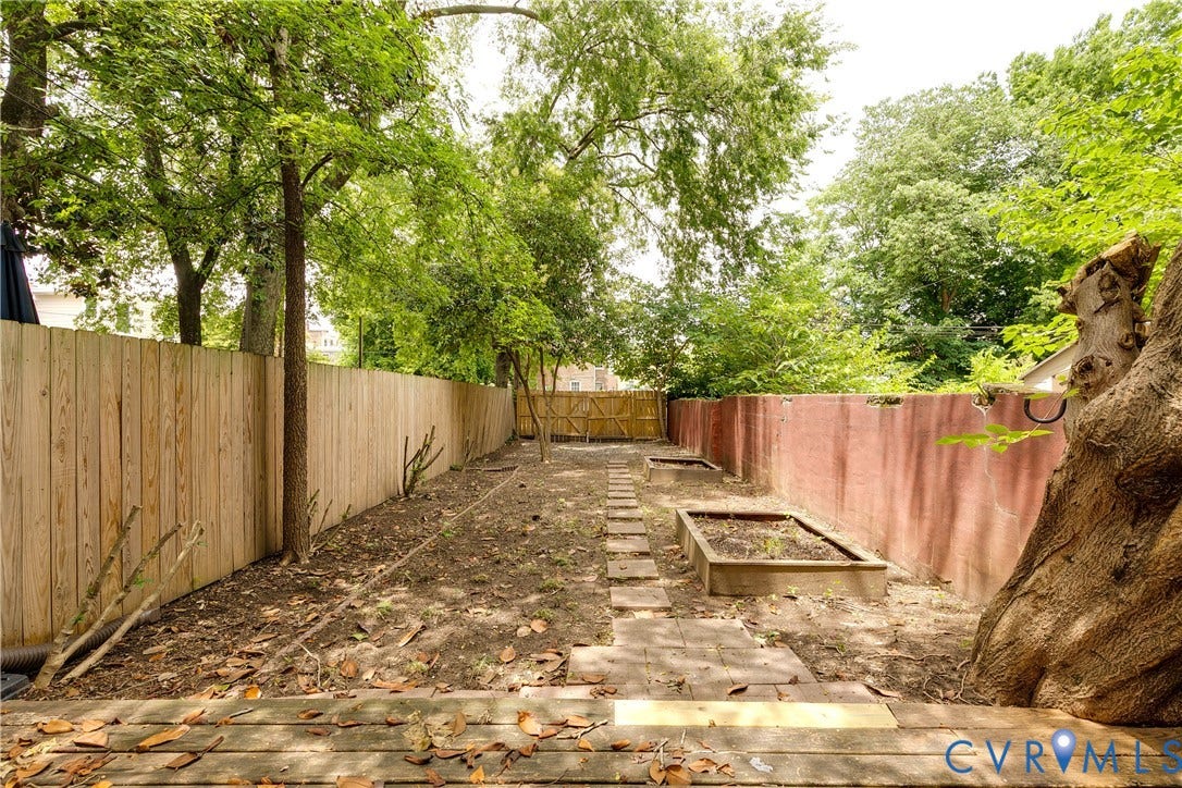 520 N 1st Street, Richmond, VA 23219 Expansive backyard featuring a new wood fence, mature perimeter trees, and integrated raised garden beds