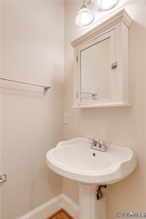 520 N 1st Street, Richmond, VA 23219 Pedestal sink with chrome faucet, wall-mounted medicine cabinet with mirror, and overhead vanity lighting