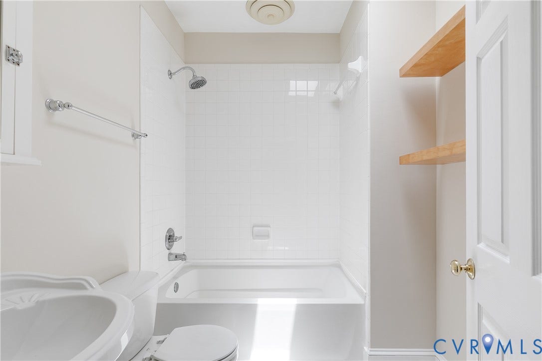 520 N 1st Street, Richmond, VA 23219 White tiled shower and tub combination with a chrome showerhead and fixtures