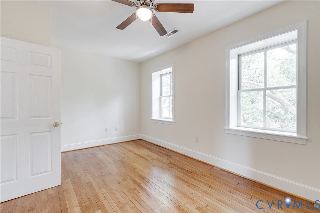 520 N 1st Street, Richmond, VA 23219 Hardwood flooring, painted interior door, ceiling fan with light, two windows, and white trim
