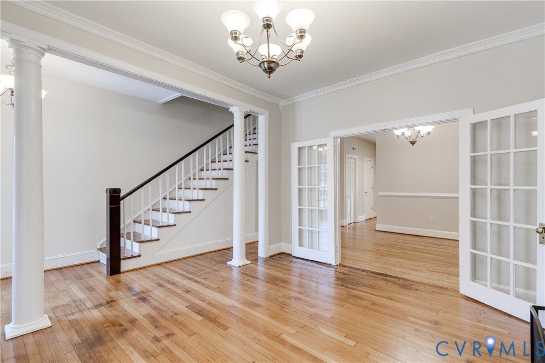 520 N 1st Street, Richmond, VA 23219 Hardwood flooring throughout, elegant staircase with dark wood handrail, classic French doors, decorative columns, and crown molding