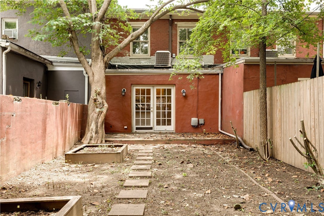 520 N 1st Street, Richmond, VA 23219 Rear exterior featuring a red stucco finish, white French doors, and two raised garden beds
