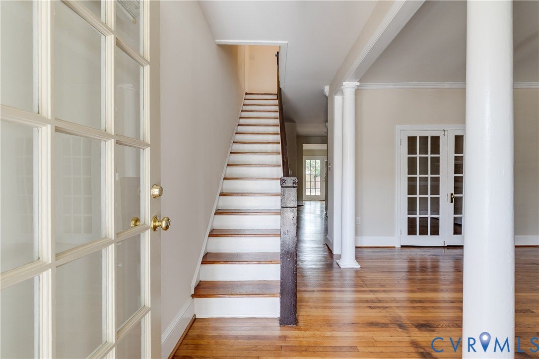 520 N 1st Street, Richmond, VA 23219 Elegant foyer and staircase featuring rich wood-finish flooring, white painted walls, and a linear staircase with wood treads and metal railings