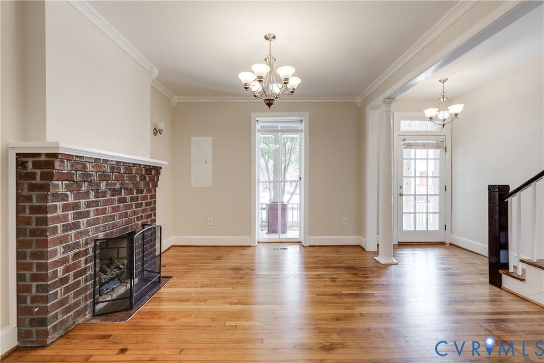 520 N 1st Street, Richmond, VA 23219 Hardwood flooring, brick fireplace with mantel, crown molding, double glass-paneled doors, and two multi-bulb chandeliers