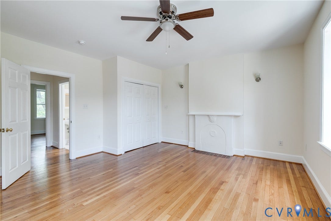 520 N 1st Street, Richmond, VA 23219 Hardwood flooring, ceiling fan, white paneled doors, built-in closet with bi-fold doors, and a decorative fireplace