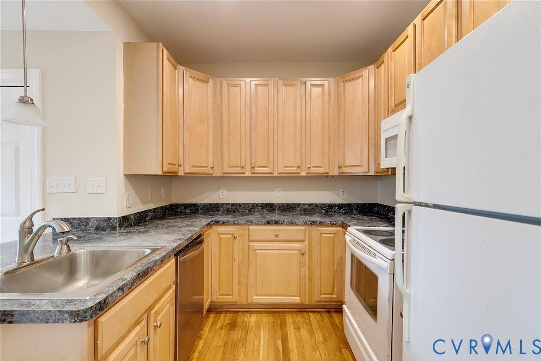 520 N 1st Street, Richmond, VA 23219 Kitchen featuring wood-finish flooring, ample cabinetry, dark patterned countertops, and a stainless steel sink with a brushed nickel faucet