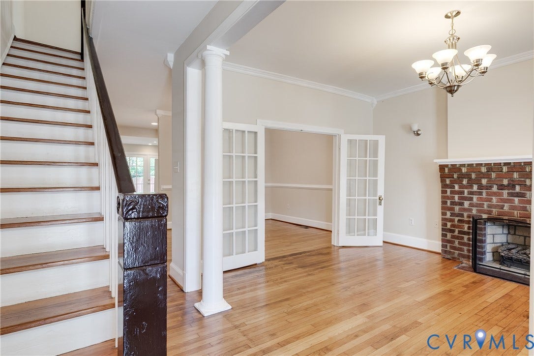 520 N 1st Street, Richmond, VA 23219 Hardwood flooring, brick fireplace with a white mantel, white French doors, painted wood staircase, and crown molding