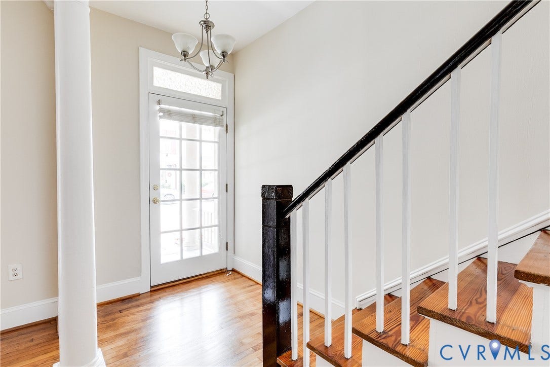 520 N 1st Street, Richmond, VA 23219 Hardwood flooring, white painted baseboards, column pillar, glass paneled door, and a three-light chandelier