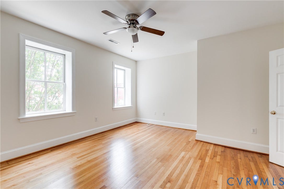 520 N 1st Street, Richmond, VA 23219 Wood-finish flooring, white trim, multiple windows with white frames, and a ceiling fan with integrated lighting