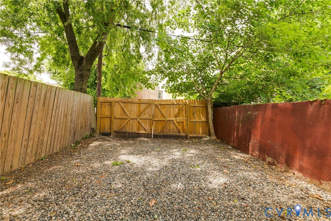 520 N 1st Street, Richmond, VA 23219 Gravel outdoor area featuring a wood privacy fence, a wood gate, and mature trees