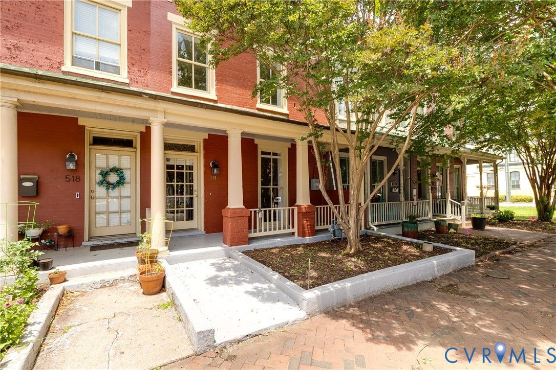 520 N 1st Street, Richmond, VA 23219 Brick facade with painted wood window frames, columned porch, and a paved brick walkway