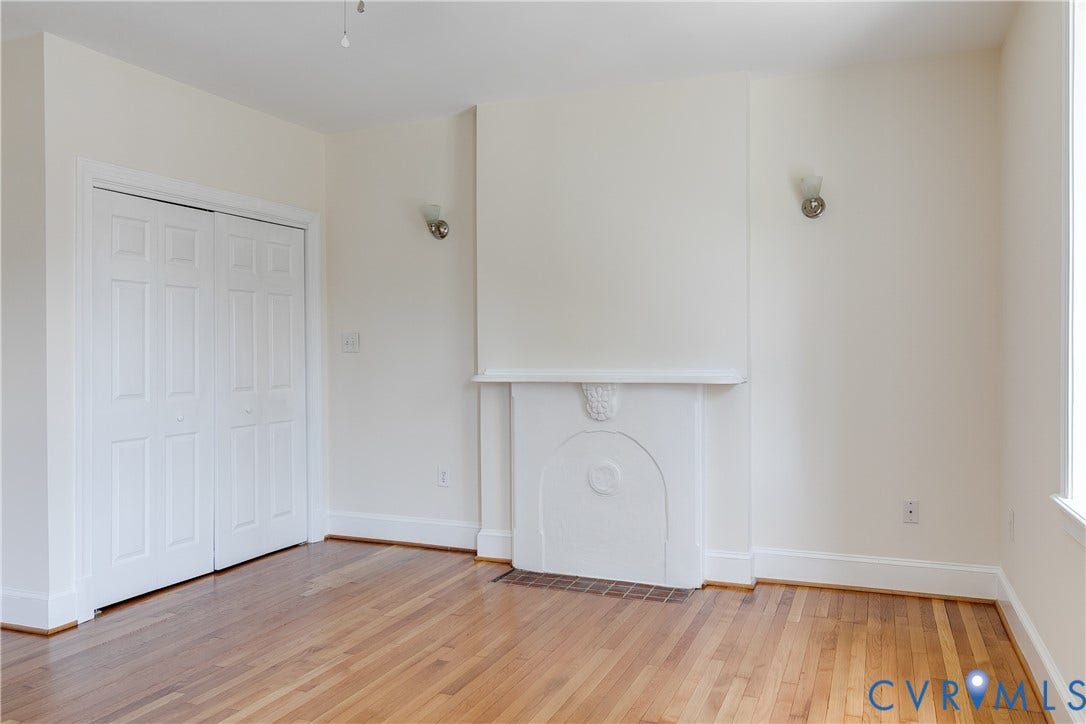 520 N 1st Street, Richmond, VA 23219 Wood-finish flooring, white bi-fold closet doors, decorative fireplace mantel, recessed fireplace, and wall-mounted sconces