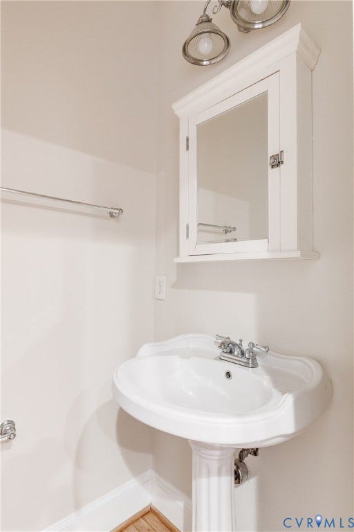 520 N 1st Street, Richmond, VA 23219 Pedestal sink with chrome faucet, wall-mounted medicine cabinet with mirror, and brushed nickel light fixture