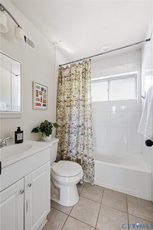 White vanity with integrated sink, white tiled shower-tub combination, and tiled flooring