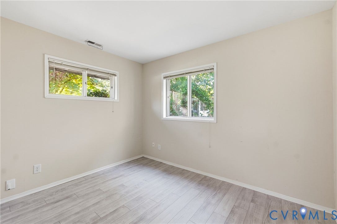 Light-toned wood-finish flooring complements the neutral wall color