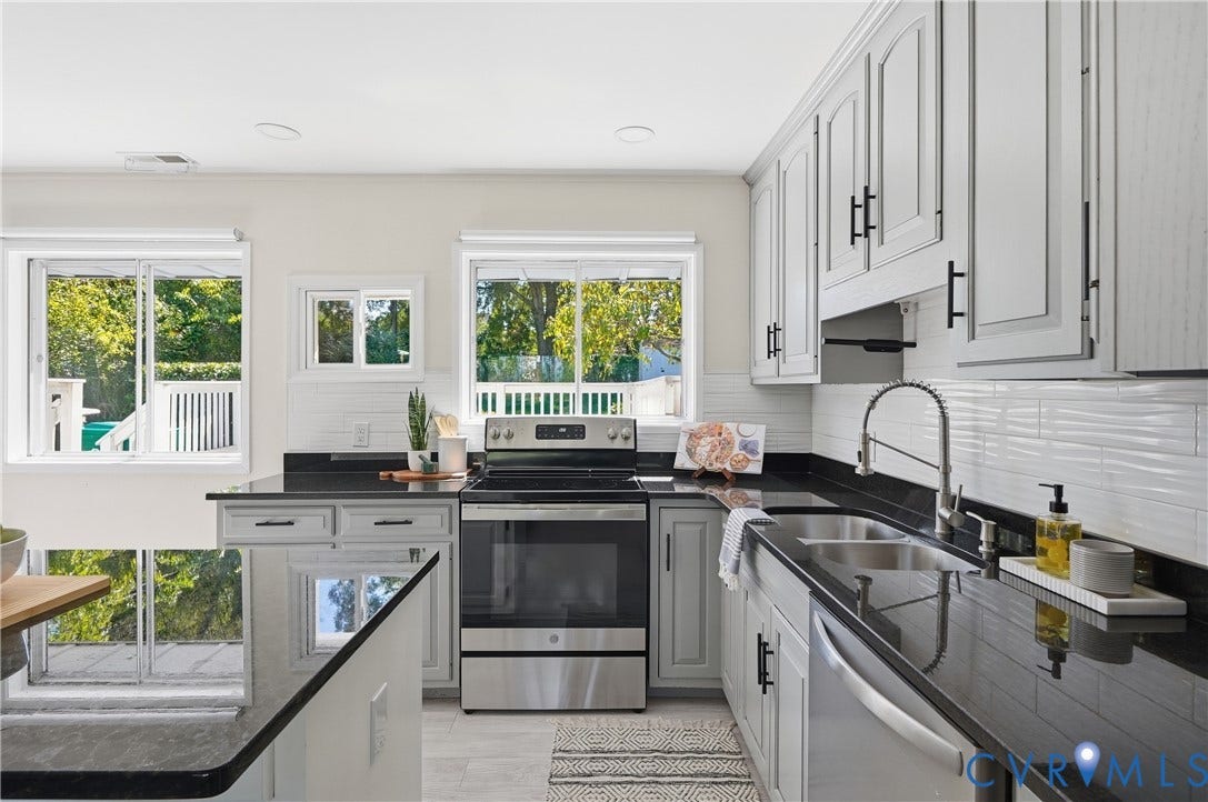 Kitchen featuring light grey cabinetry, dark countertops, a stainless steel appliance suite, and a white tile backsplash