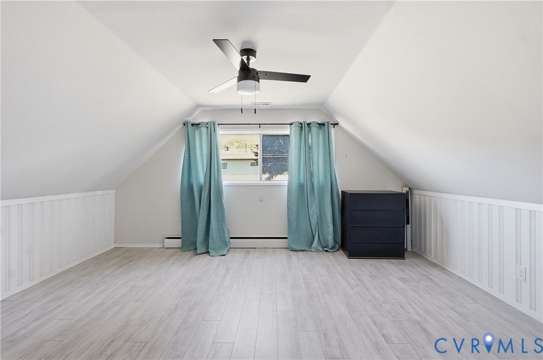 Wood-finish flooring, white paneling, ceiling fan, and sloped ceilings