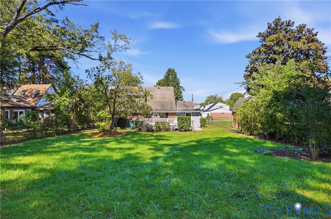 Expansive green lawn with mature trees and established landscaping