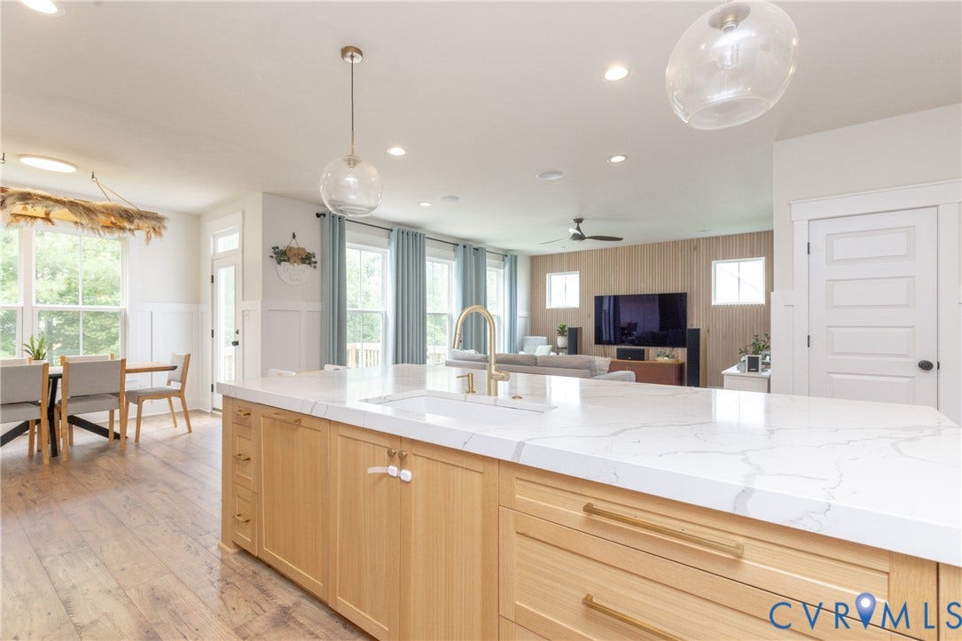 Expansive kitchen island with a light-toned countertop, integrated sink, and gold-finish faucet