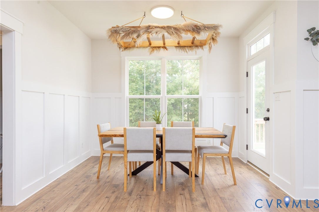 Wood-finish flooring, white board and batten wall treatment, large window with transom, glass-paneled door with transom, and recessed ceiling lighting