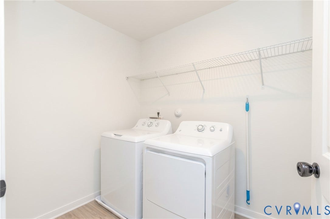 Laundry area with wood-finish flooring, white walls, and built-in wire shelving