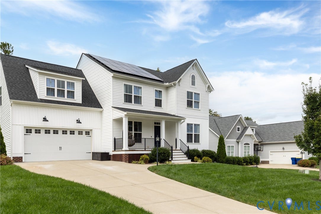 Two-story residence featuring white siding, a covered front porch with black railings, and a two-car garage with carriage-style doors