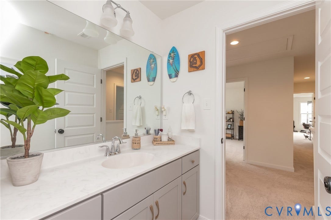 Vanity with an integrated sink, brushed nickel faucet, and a wall-mounted mirror