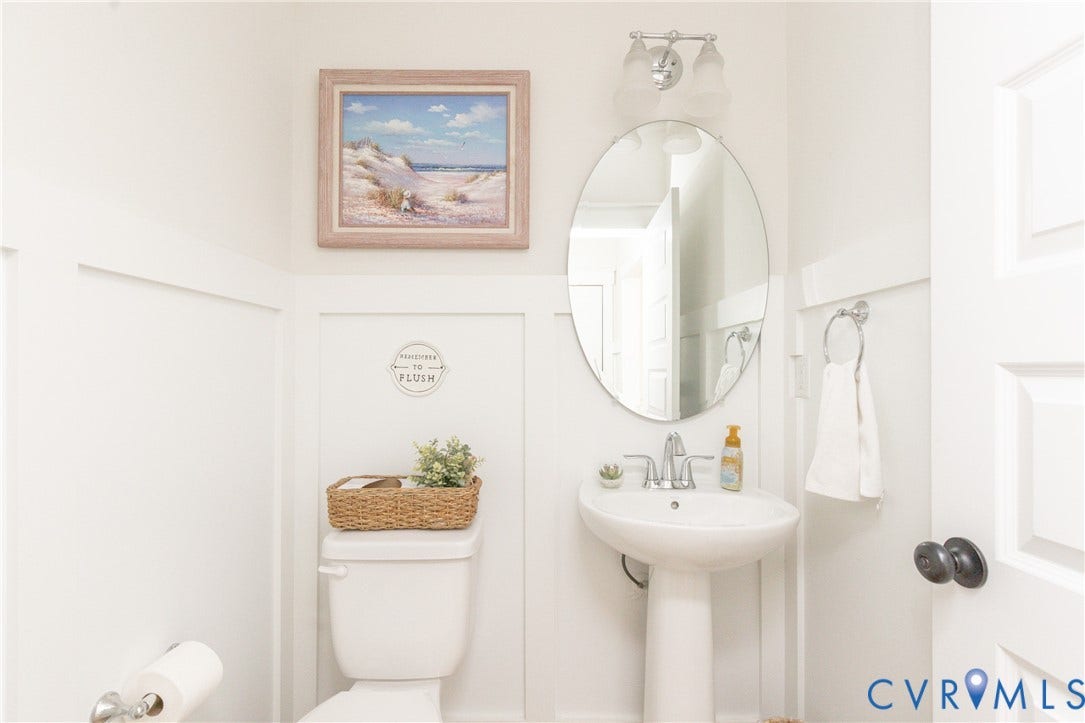 White board and batten wall paneling, pedestal sink with chrome faucet, oval wall mirror, and chrome vanity light fixture